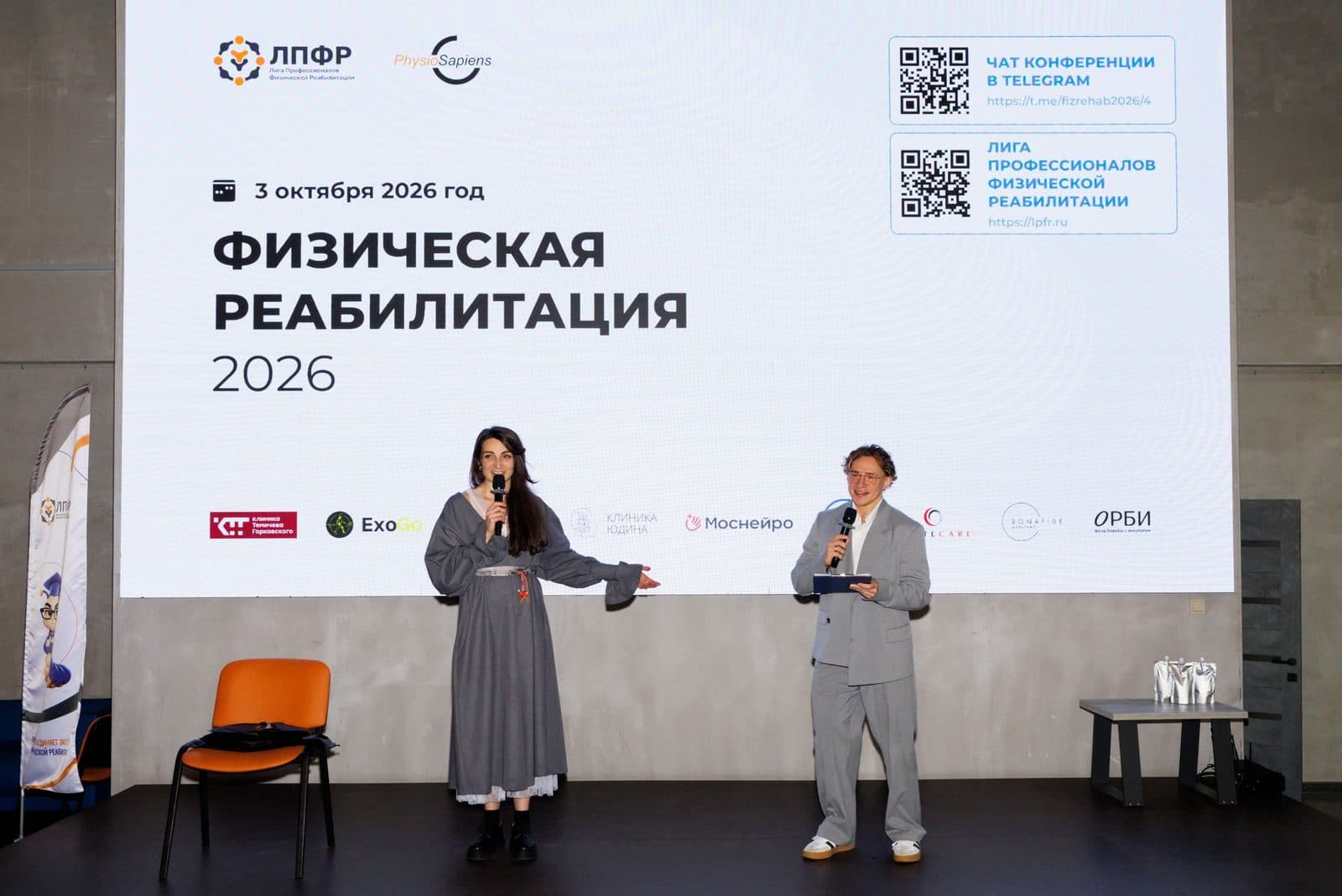 Ведущие на сцене, на экране логотипы партнёров конференции с ExoGo