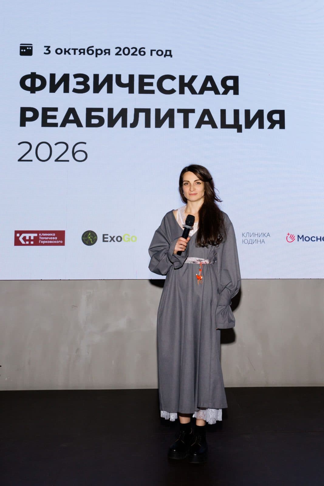 Ведущая конференции на фоне экрана с логотипом ExoGo